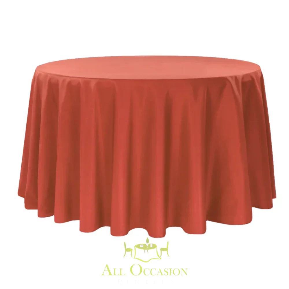 132 inch round polyester tablecloth burnt orange displayed on a large round table.