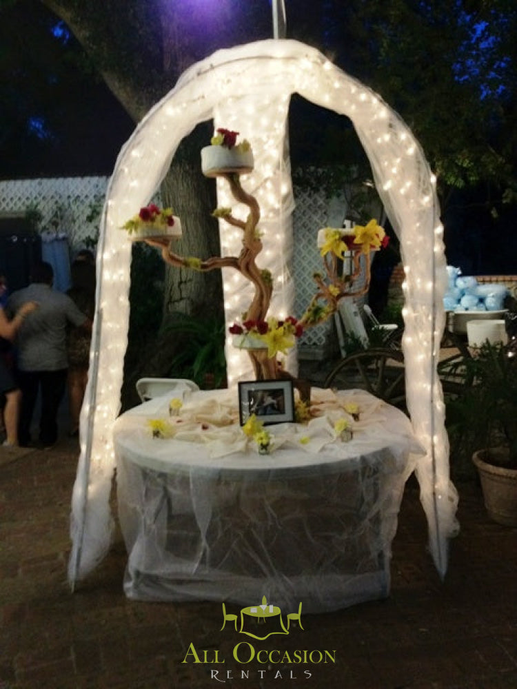 Tree wedding cake stand adorned with lights and flowers, perfect for receptions from Corona event rentals.