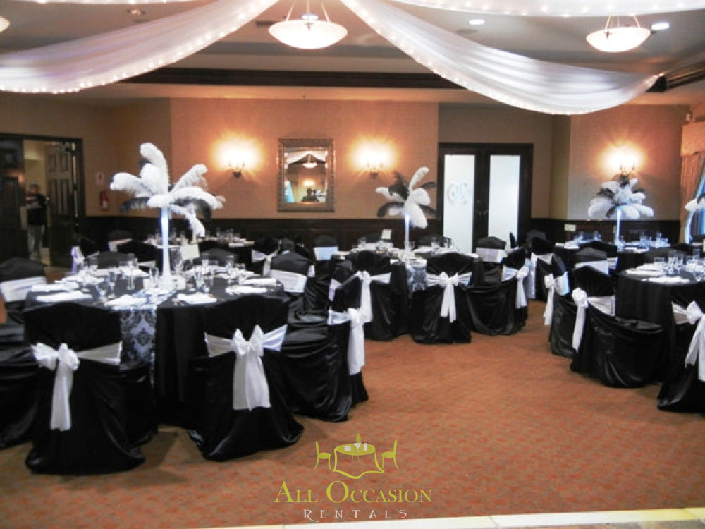 Elegant event setup featuring Feathers Centerpieces with stylish table linens and chair rentals in Corona.