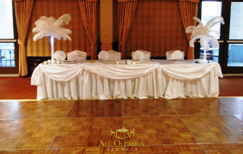 Elegant feathers centerpieces at a banquet for event rentals in Corona, accented with draped table linens and a dance floor.