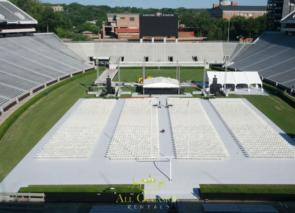 Outdoor event setup with white chairs and tent for Corona event rentals in a stadium.