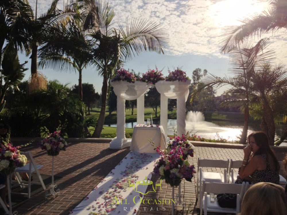 Elegant wedding columns set up for a ceremony in Corona, featuring lush floral arrangements and scenic views.